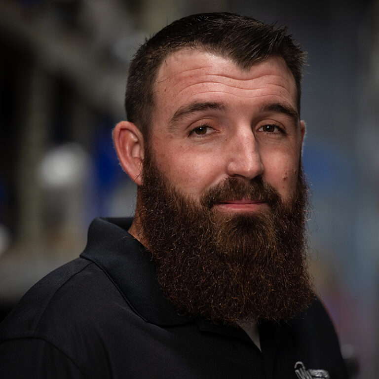 Austin McCauley, Service Manager, depicted as a man with a beard in a black shirt.