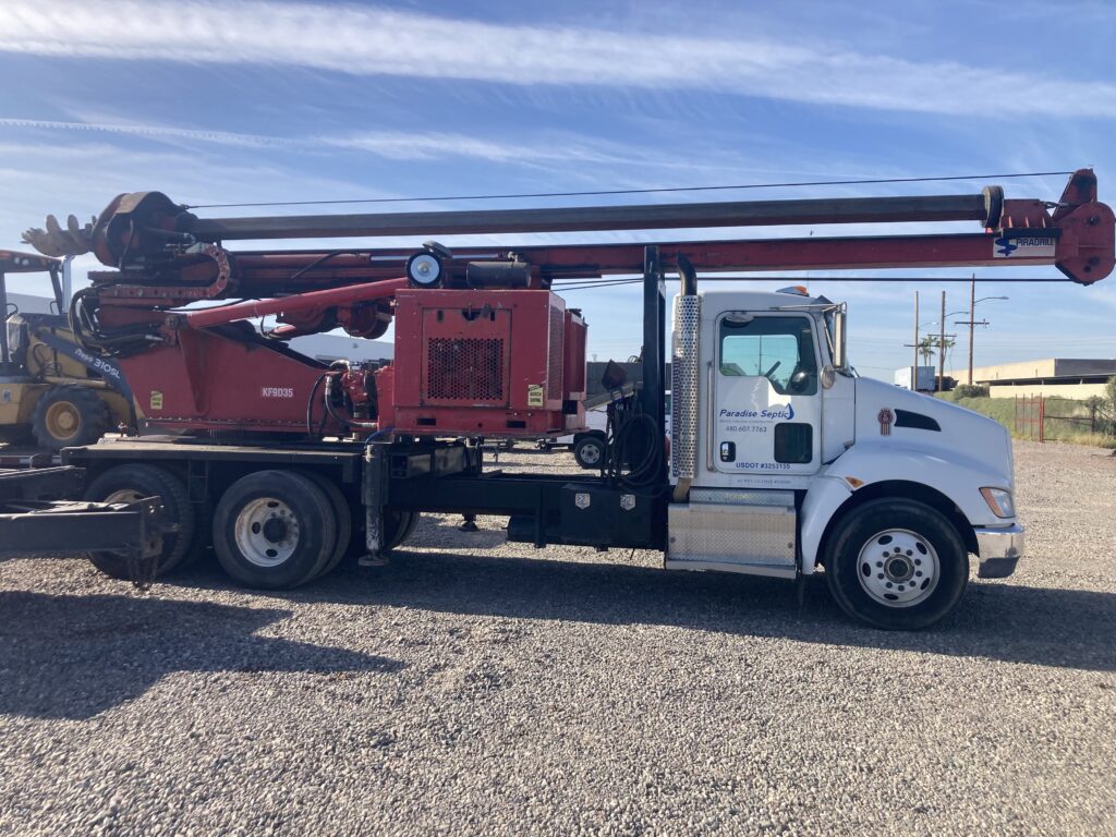 A red and white truck with a crane and a backhoe on it, ready for heavy lifting and construction work.
