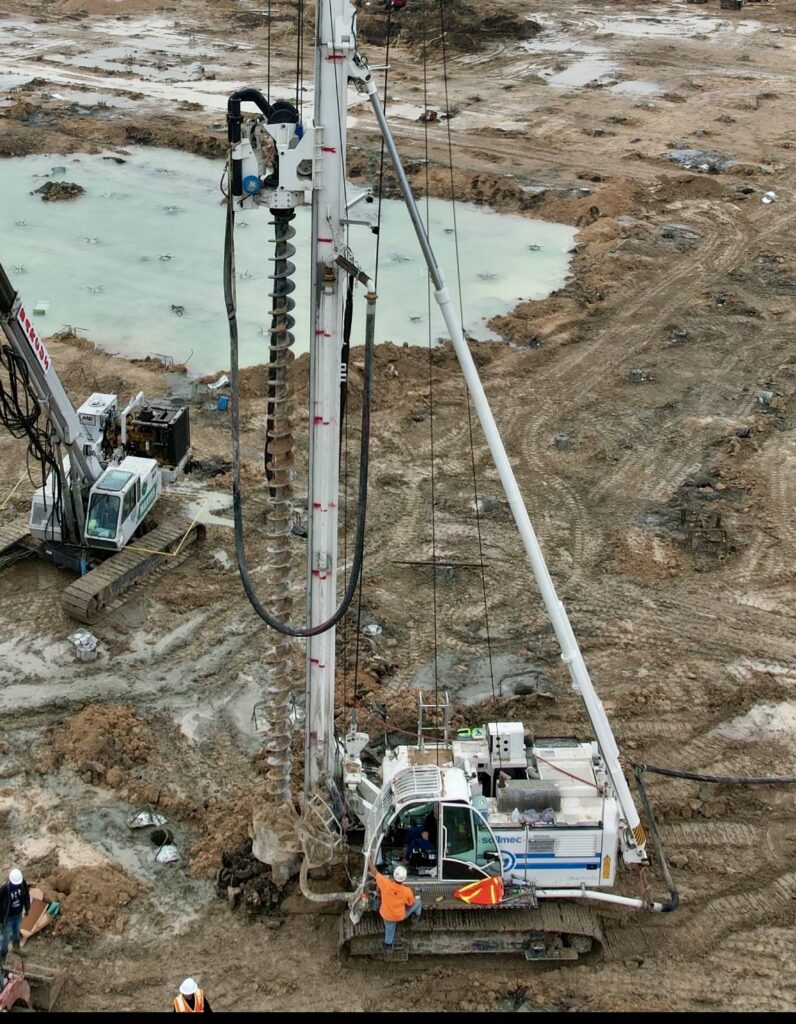 A drilling rig with a backhoe is drilling a hole.