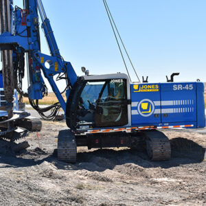 A blue and white machine on a dirt field, possibly a tractor or construction equipment.