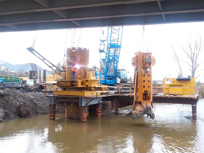 A crane lowering a large machine into the water.