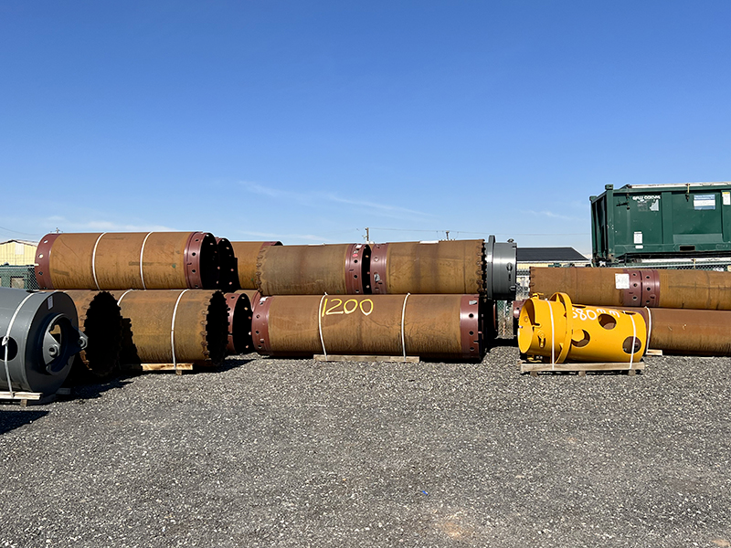 Several large steel pipes on top of a pile, ready for use in a dam construction project.