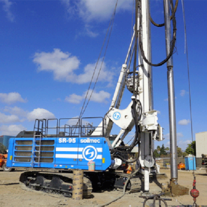 Drilling rig in blue and white colors, set up on a dusty field.