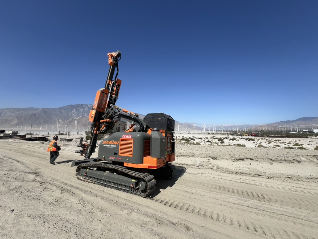 Construction machine in desert with drilling equipment for short-term project, using rental equipment.