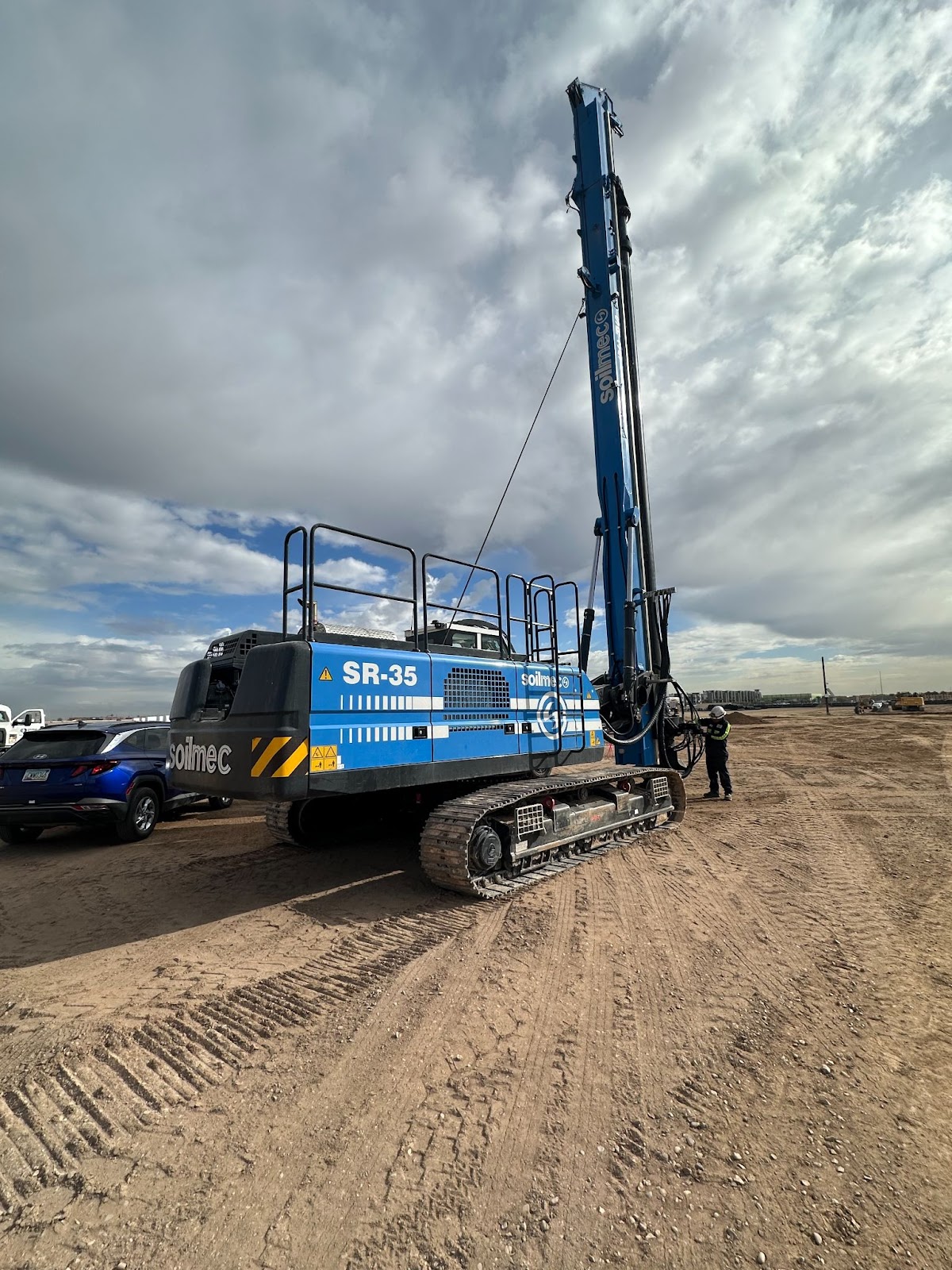 A blue drilling rig for foundation equipment solutions, depicted atop dirt, showcases the expertise of foundation drilling.