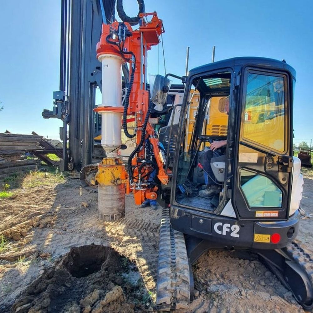 A crane-operated machine drilling into the ground.