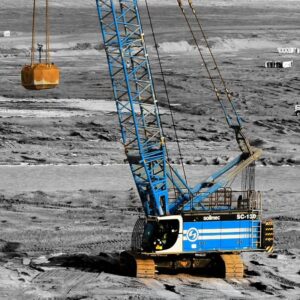 Crane hoisting a big pipe in the sand at a construction site