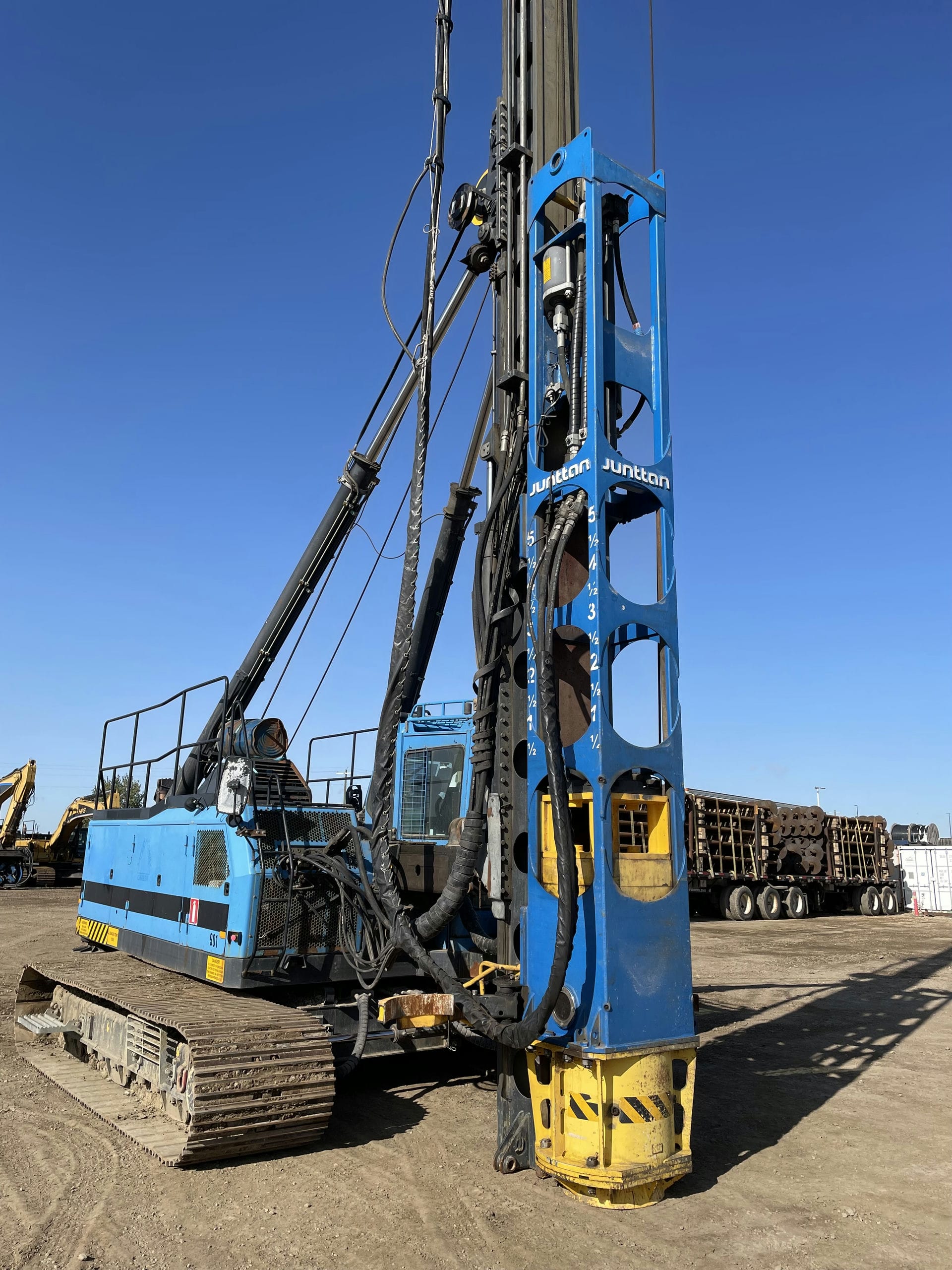 A blue drill rig on a dirt field, ready for work.