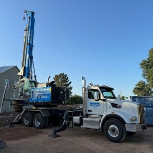 Blue and white truck with crane on top, parked on construction site