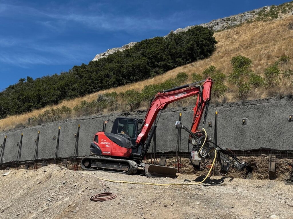 A red excavator is engaged in construction work operating on a wall to modify or repair it
